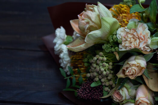 Buket av blandade blommor i olika färger på mörkt bord.