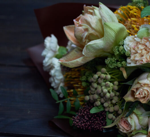 Buket av blandade blommor i olika färger på mörkt bord.