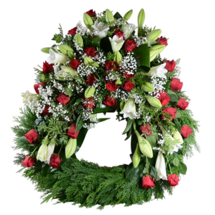 En stor krans dekorerad med röda rosor, vita liljor och gröna bladverk, arrangerad i en cirkulär form.
